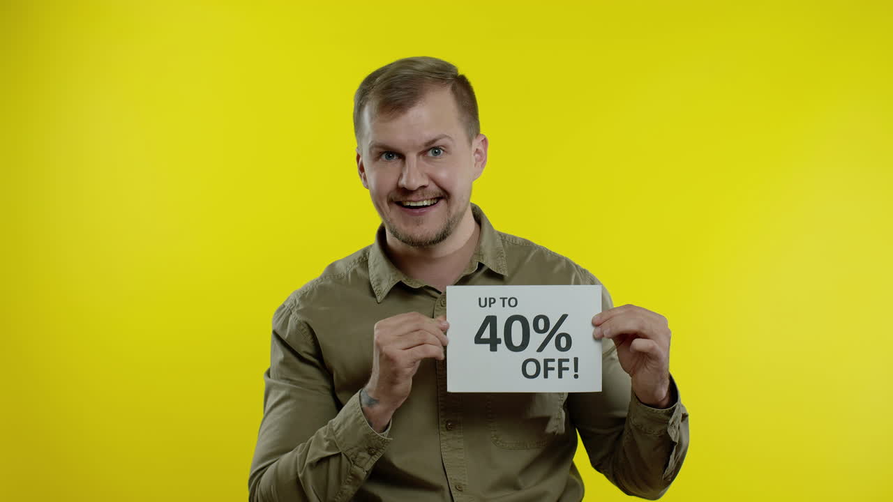 hombre atractivo mostrando hasta un 40 por ciento de descuento inscripciones señales, regocijándose buenos descuentos, precios bajos