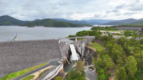 water flows over dam surrounded by lush landscape