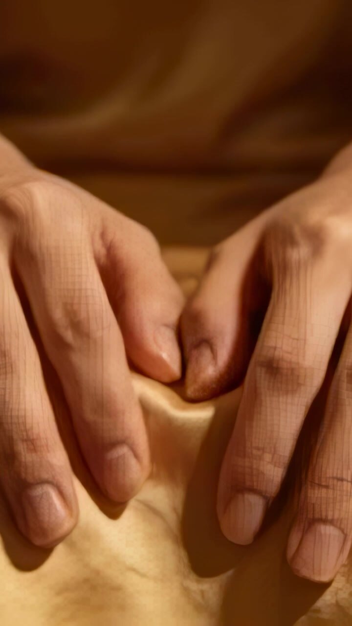 Vidéo verticale : Mains nues pressant après le repos, lissant du satin doré sur les genoux et créant des plis.