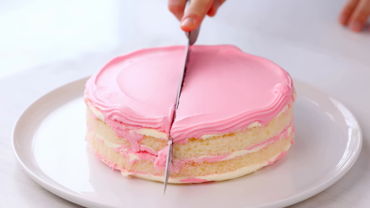 Mano che taglia una torta a strati rotonda con glassa rosa