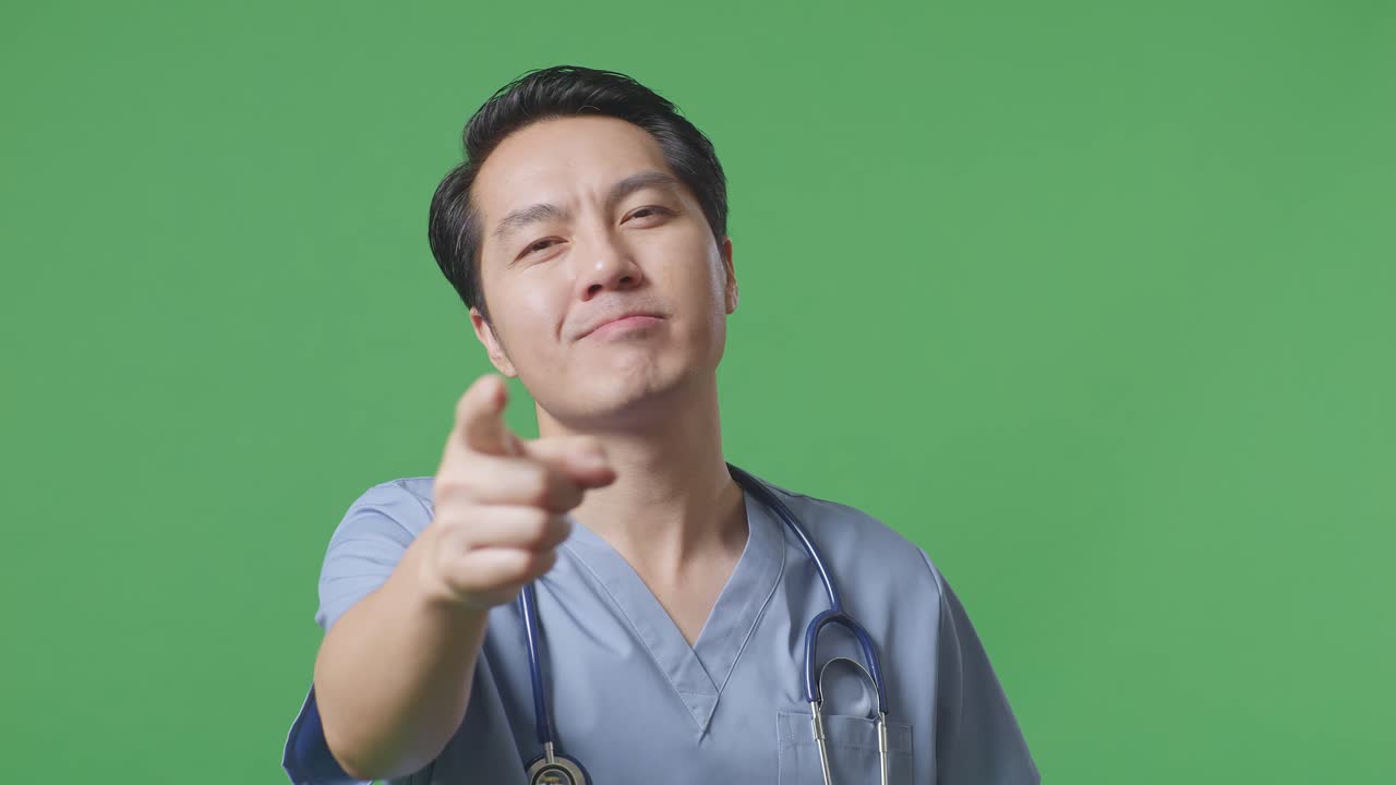 스테토스코프를 들고 있는 아시아 남성 의사의 근접 사진. 병원의 녹색 스크린 배경에서 정직한 몸짓을 하고 웃는 모습.