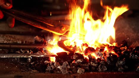 Close-up-of-blacksmith-heating-a-horseshoe-in-fire