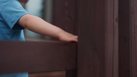 niño pequeño toca la viga húmeda de la barandilla caminando por la veranda
