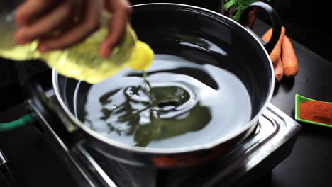 man put one bottle of oil in a hot cooking pan for frying chicken lollipop pieces and prepare chinese food