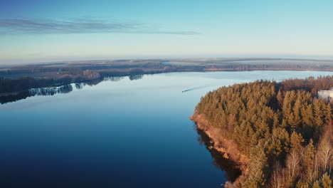 calm lake in the evening. boat moving on the river at sunset. beautiful nature background. trees reflected in water. aerial view.