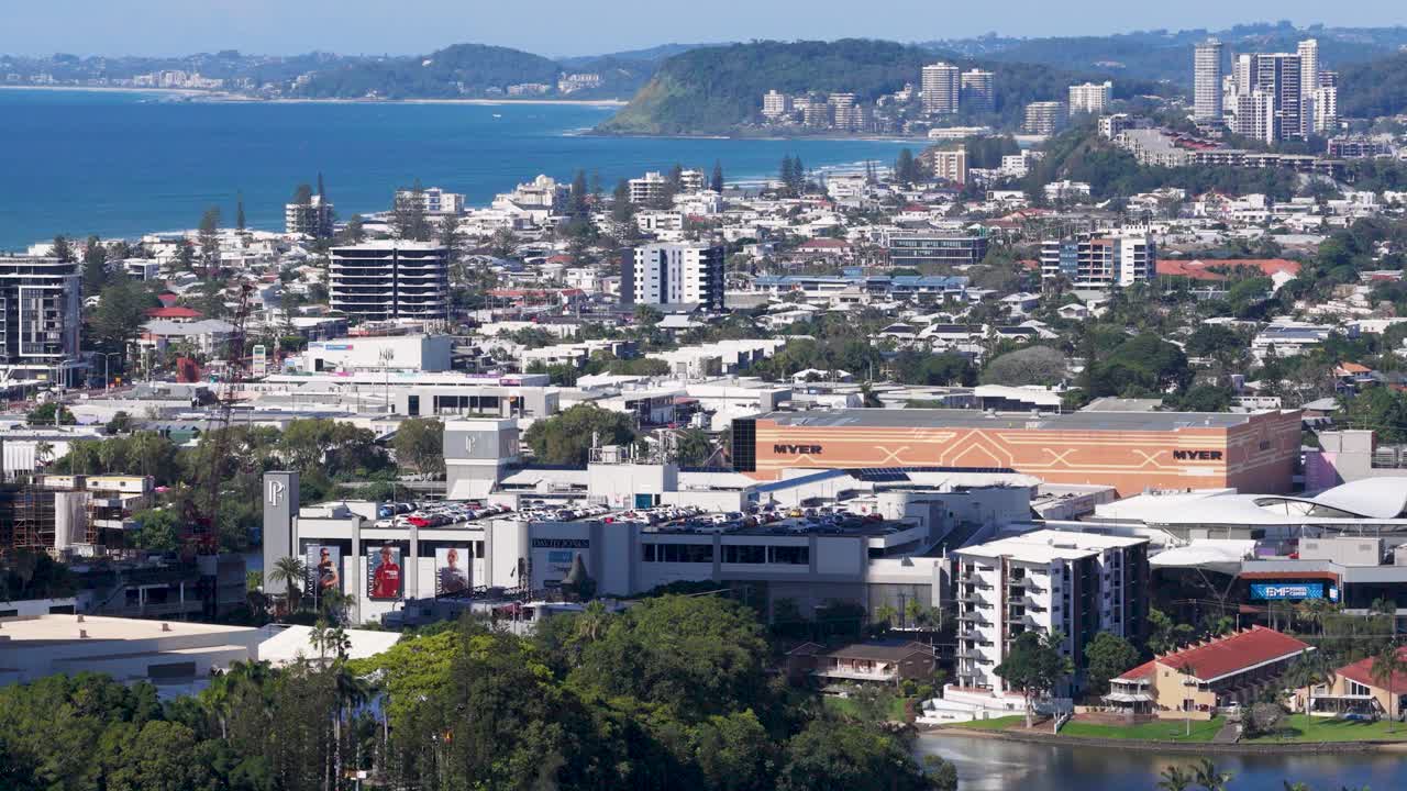 Drone footage captures urban landscape, roads, and coastline under clear skies with vibrant colors and dynamic movement