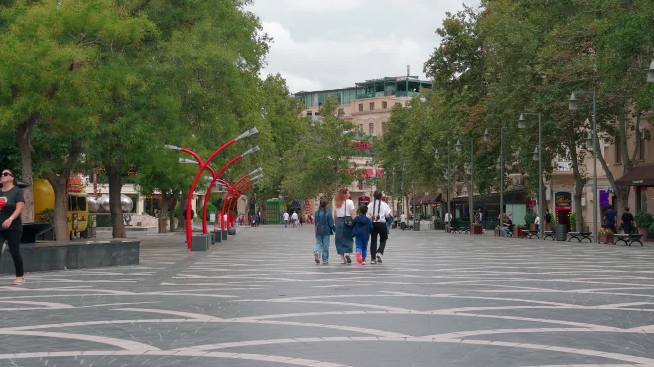 People Walking on a City Street with Trees and Buildings