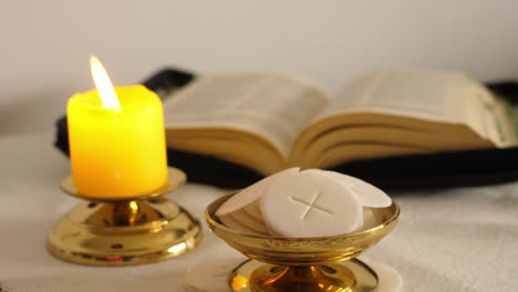 communion hosts lit candle and holy bible