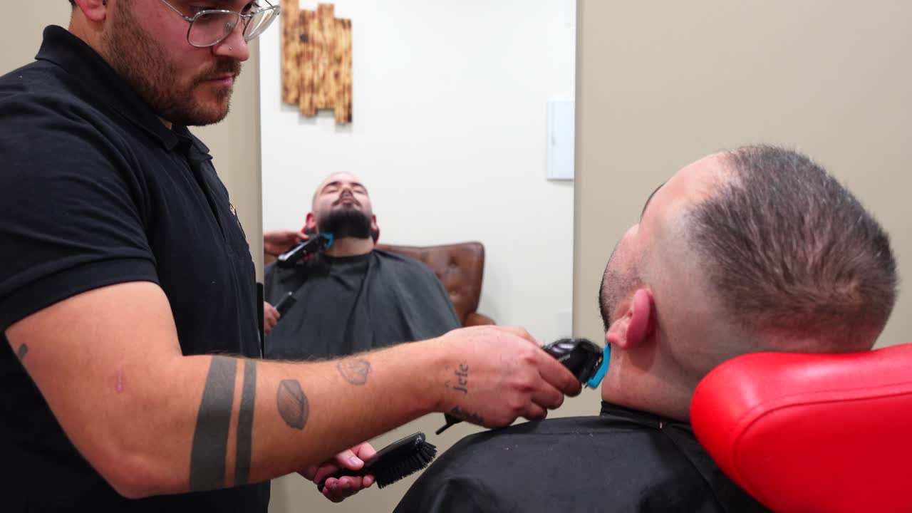 Profile shot of barber trimming customer beard then fitting a razor head to continue precise shave and shaping