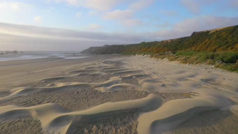 Drone-Volando-Hacia-Atrás-Cerca-Del-Suelo,-Revelando-Patrones-En-La-Arena-De-Una-Playa-De-Oregon-Llamada-Whisky-Run-Cerca-De-Bandon