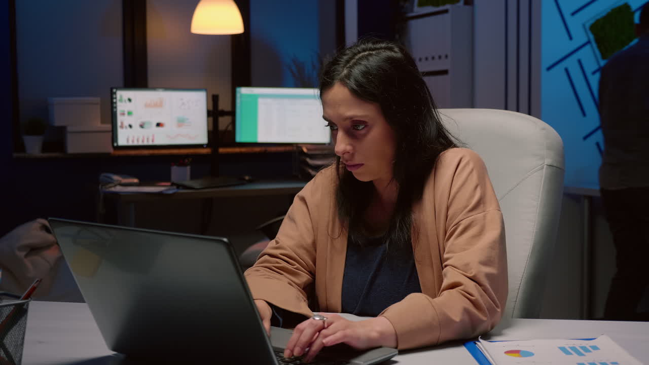 mujer de negocios cansada y sobrecargada de trabajo frotándose la cara trabajando en estadísticas de gestión