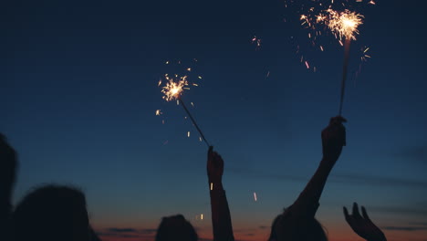 friends celebrating at sunset by the lake with sparkler