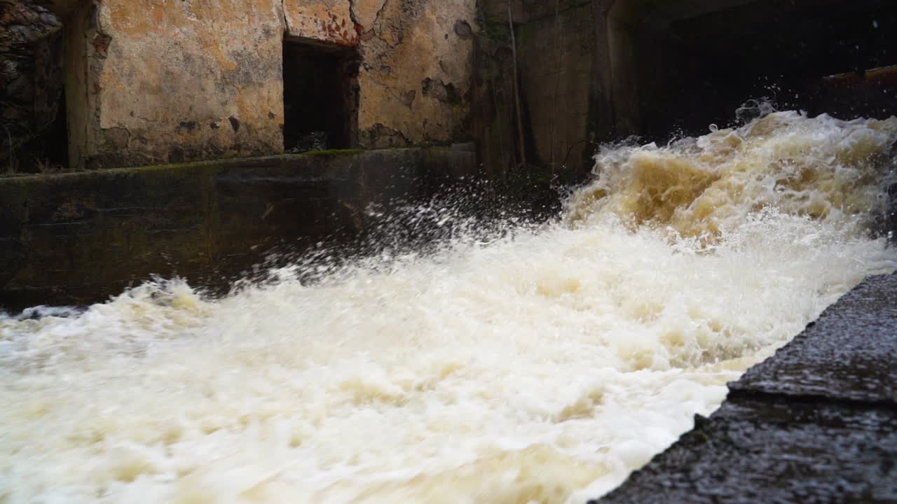 Splashing and foamy river water crashing down the waterfall in slow motion