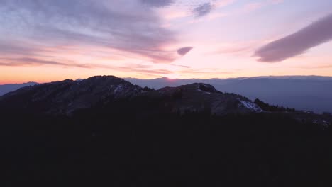 silhouette aerial view flying forward during sunset in winter with snow on mountain peaks in madrid, spain