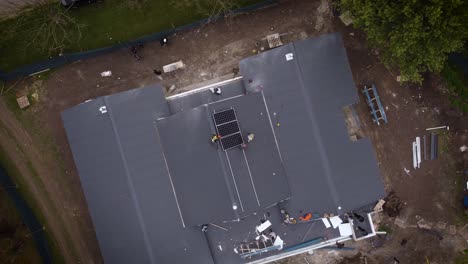 trabajadores irreconocibles instalan paneles solares en el techo de una casa nueva.