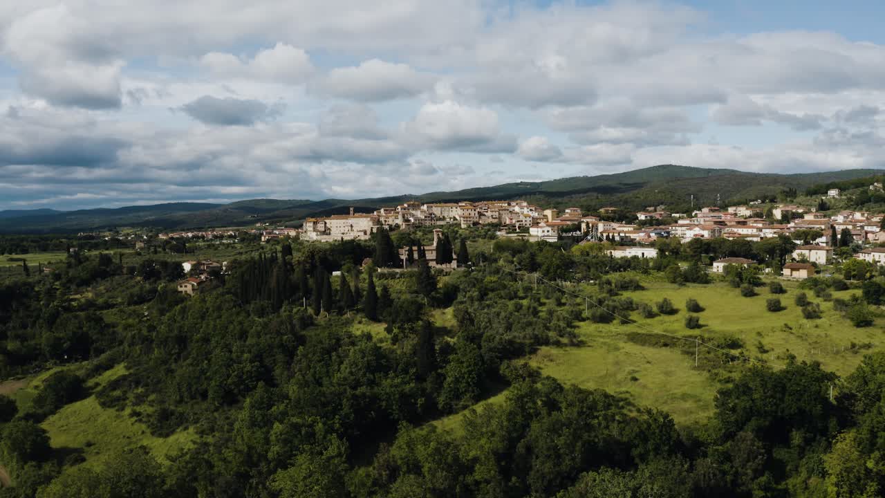 Wide drone shot pulling away from the quaint town of Rapolano Terme nestled in Italy's countryside