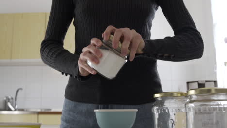 plano medio como una mujer abriendo un frasco lleno de azúcar de abedul blanco, concepto de dulces saludables