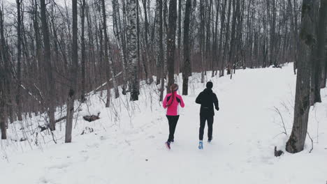 man and woman in the winter running through the park in slow motion.