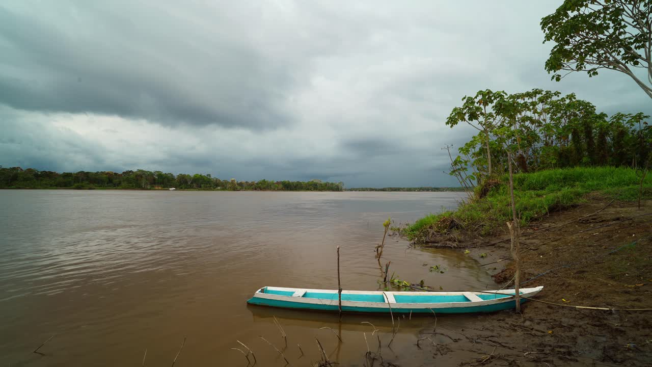 Static timelapse of clouds over boat by shore of Amazon River, Brazil