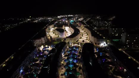 this nighttime aerial video showcases a brightly illuminated urban area phu quoc where distinctive multi-story buildings line curving, lavishly lit pathways visually appealing and vibrant urban space.