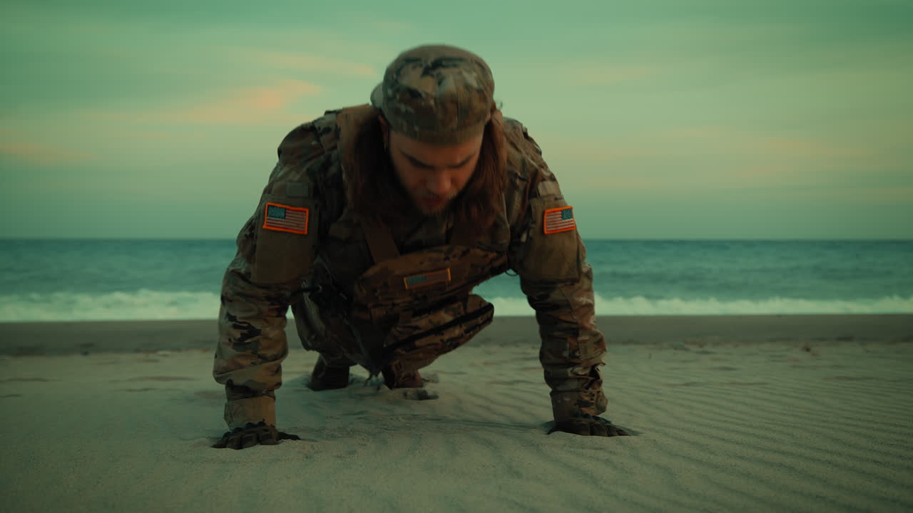 Amerikansk soldat laver armbøjninger på stranden som træning nær havet