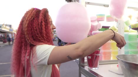 woman pays for cotton candy at a fair stall