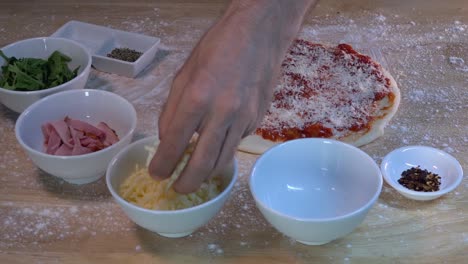 topping a pizza with grated mozzarella