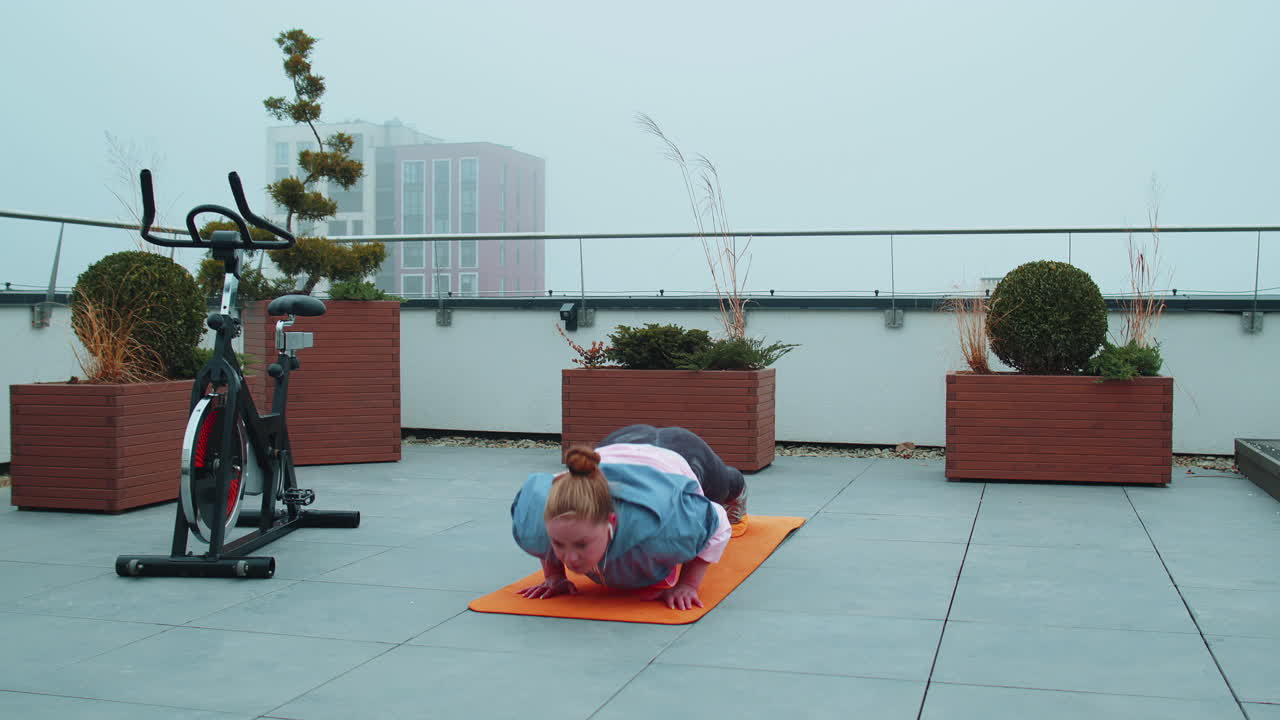 mujer atlética hace ejercicios de flexiones, fitness cruzado, rutina de entrenamiento de culturismo en el techo de la casa