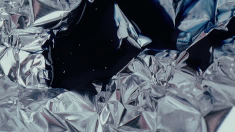 abstract crumpled foil with dark liquid
