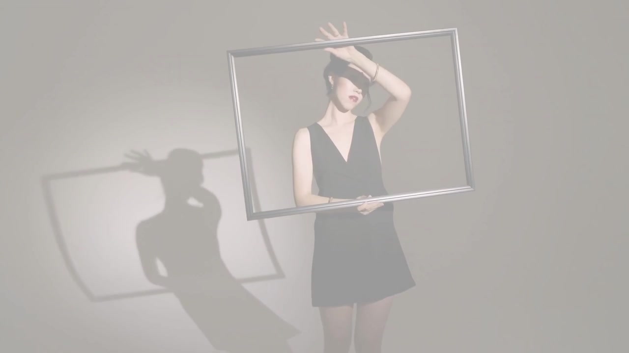 スポットライトが当たる中、フレームを持つ中国人女性がそれを傾けたり回転させたりすると、影が変化し、カメラがズームインする。