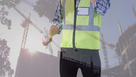 Animation-of-building-site-over-caucasian-male-worker-talking-on-smartphone