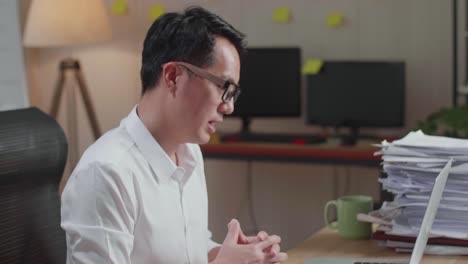사무실 에서 문서 를 처리 하는 동안 노트북 으로 비디오 통화를 하는 아시아인 의 근접 사진
