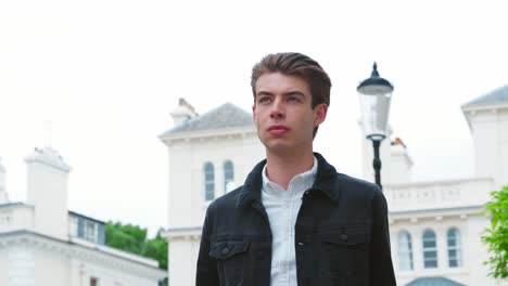 stylish young man carrying coffee walks along city street