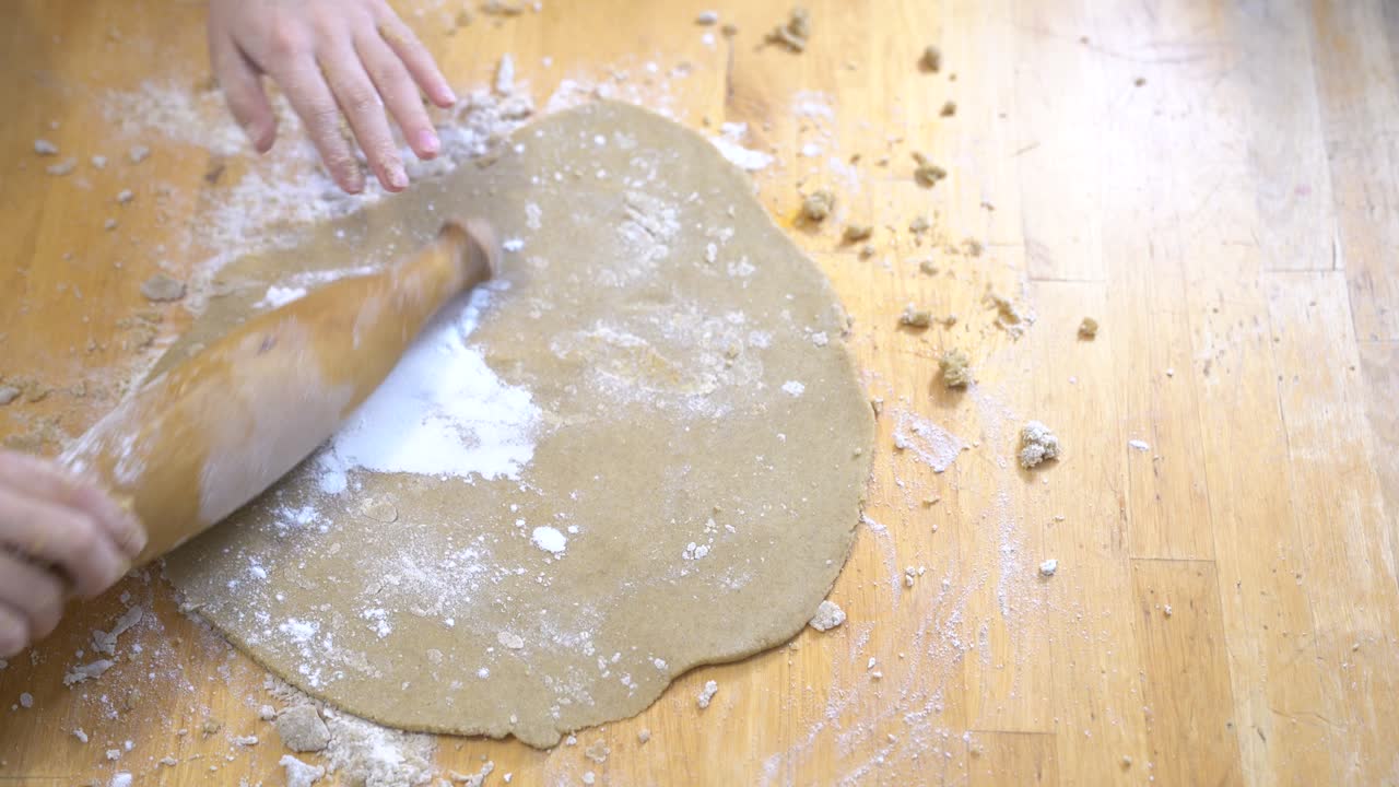 The girl rolls out the Gluten-free dough for pizza or cookies. Cooking together.