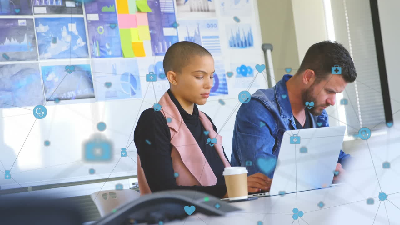 Animation of network of digital icons over diverse man and woman working at office