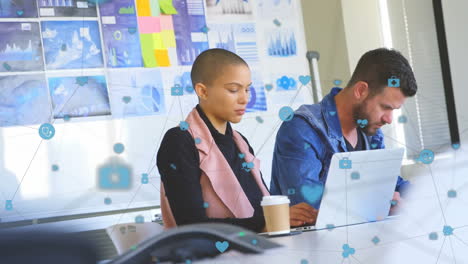 animation of network of digital icons over diverse man and woman working at office