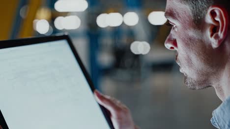 engineer reviewing technical drawings on tablet in a factory