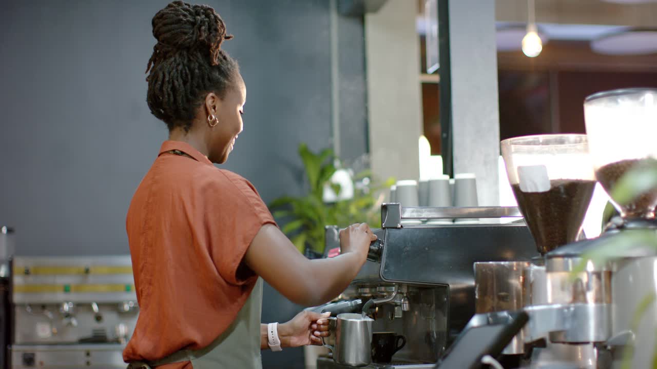 Woman barista reacting to POS alert at counter using espresso machine steaming pitcher for customer