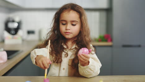 child painting easter eggs in kitchen