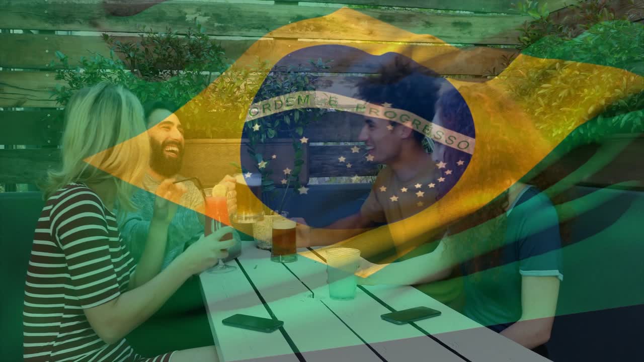 笑顔の友人4人がグラスを掲げ乾杯し、スマートフォンを片手に食事。ブラジル国旗の色調。