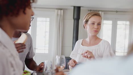 gruppe junger freunde sitzt zu hause um den tisch und genießt gemeinsam eine mahlzeit