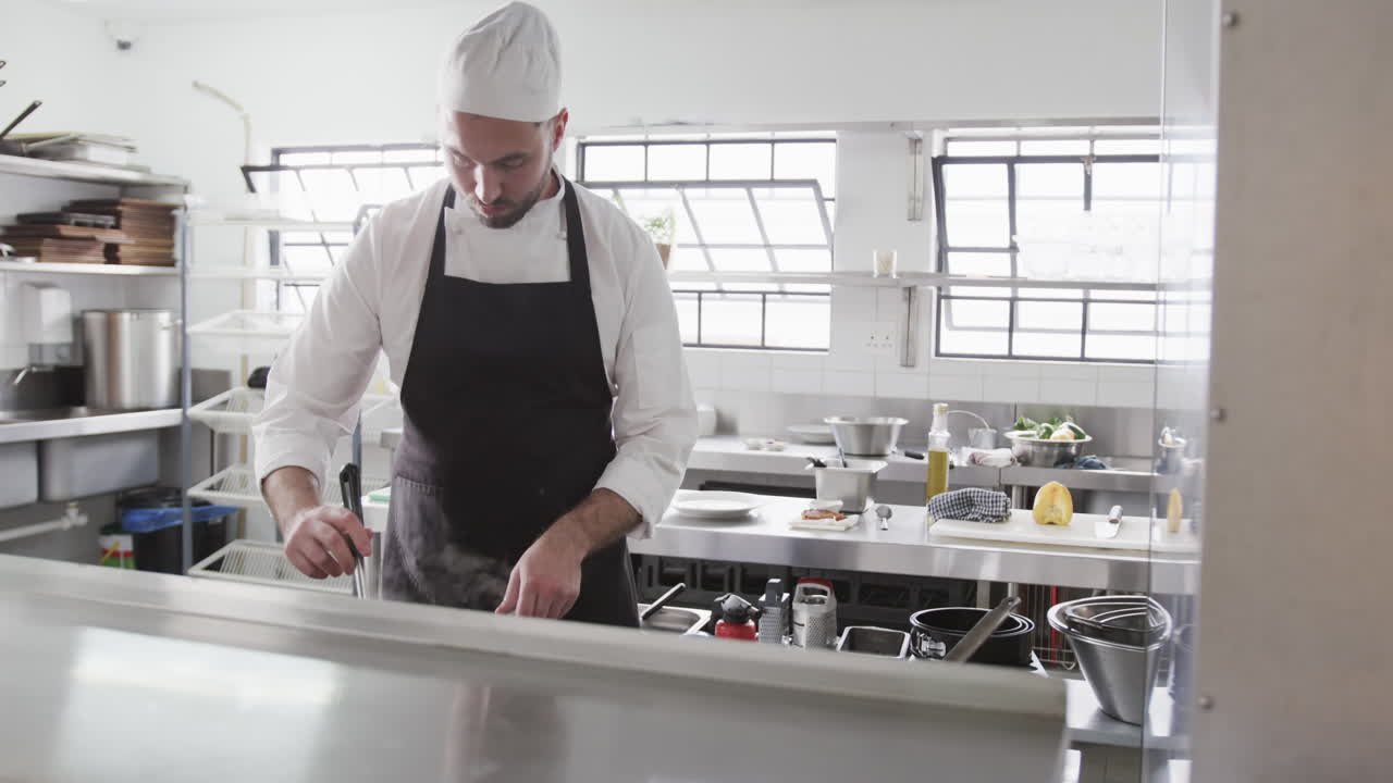 Chef maschio caucasico concentrato che prepara un pasto in cucina, al rallentatore