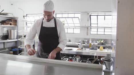 focused caucasian male chef preparing meal in kitchen, slow motion