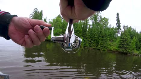 Behind-close-shot-of-spinning-fishing-reel-with-fish-on-the-line,-in-the-Whiteshell-Provincial-Park,-Point-du-Bois-near-Winnipeg-Manitoba-Canada