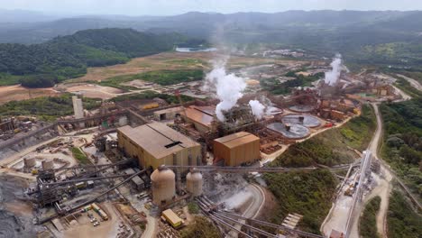 Tanks, clarifier and smoke chimney in Cotui, industrial gold refinery, aerial orbit