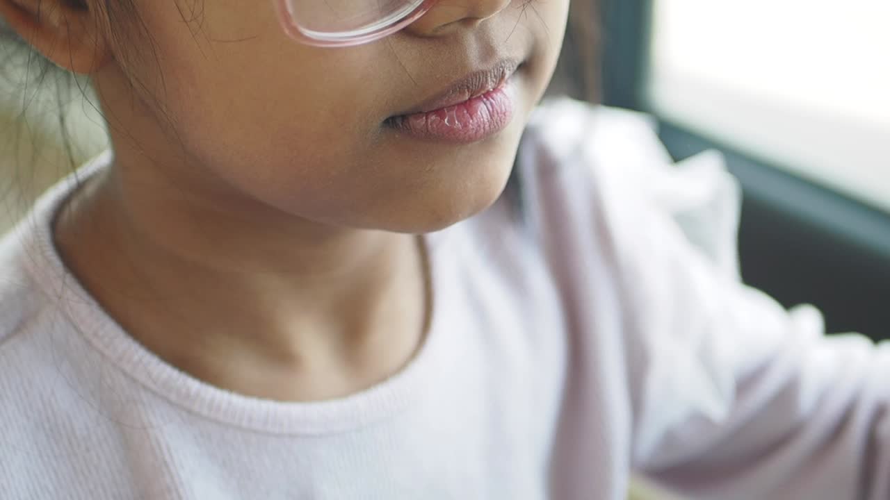 분홍색 안경을 입고 손가락을 는 미소 짓는 어린 소녀의 클로즈업