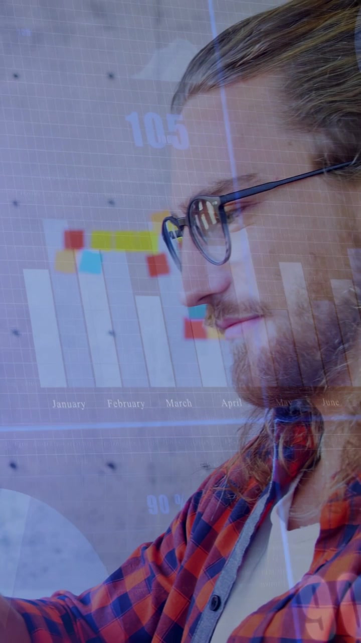 Vertical video: Seated man tapping tab and causing data charts over notes wall for business review