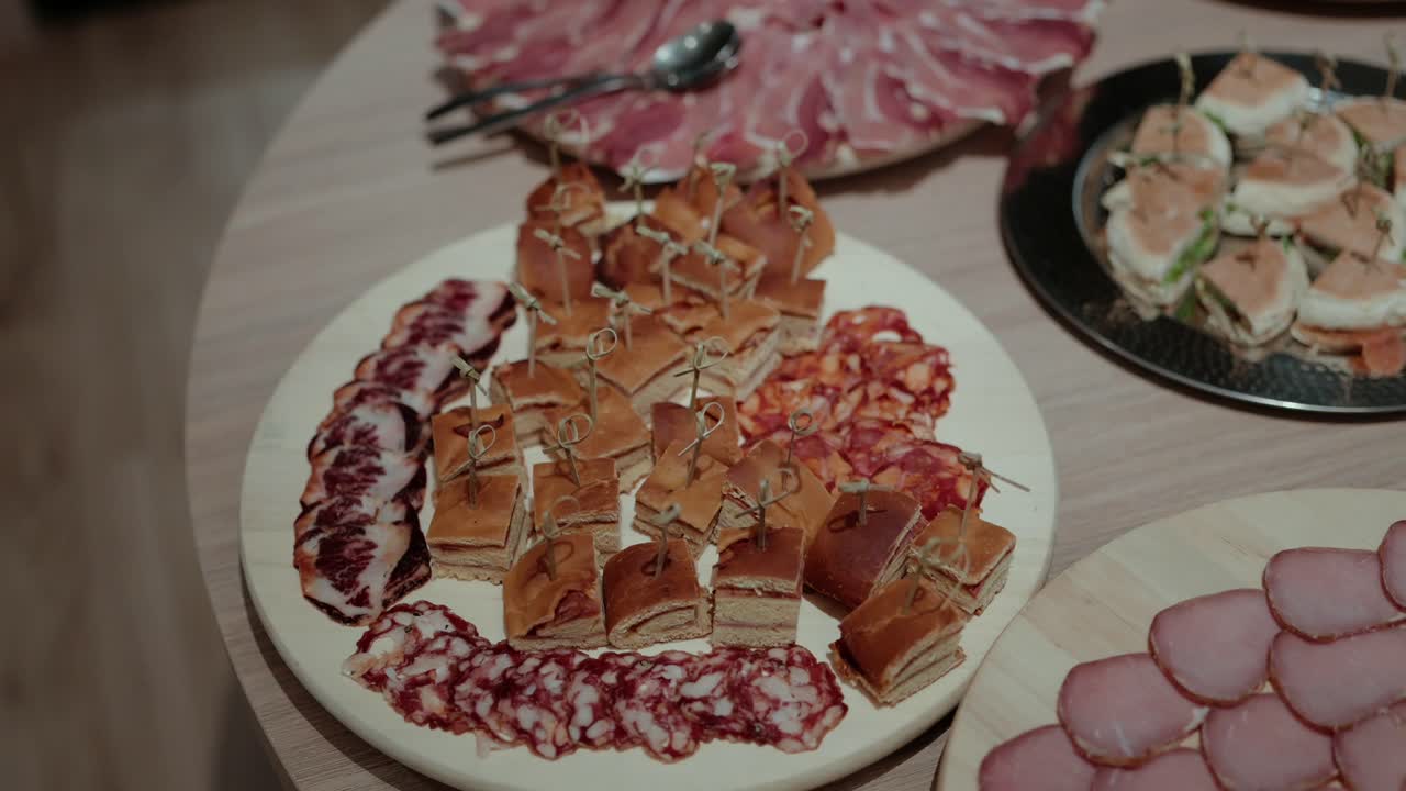 Close view of appetizer platter with mini sandwiches and cured meats