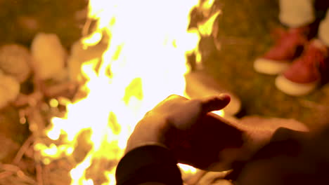 close up de un turista sentado cerca del fuego del campamento por la noche