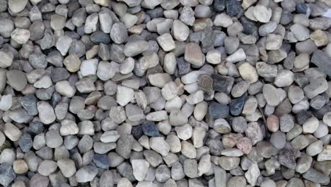 background of large pile gray gravel stone pebbles, used in construction, turning slowly.